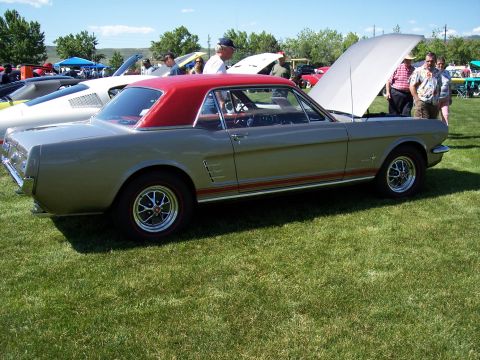1972 Ford Ranchero - A silver 1965 Ford Mustang coupe with a red vinyl top is displayed at an outdoor car show.