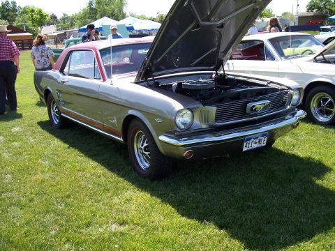 1972 Ford Ranchero - A silver 1965 Ford Mustang is displayed with its hood open at a car show, parked next to another vehicle.