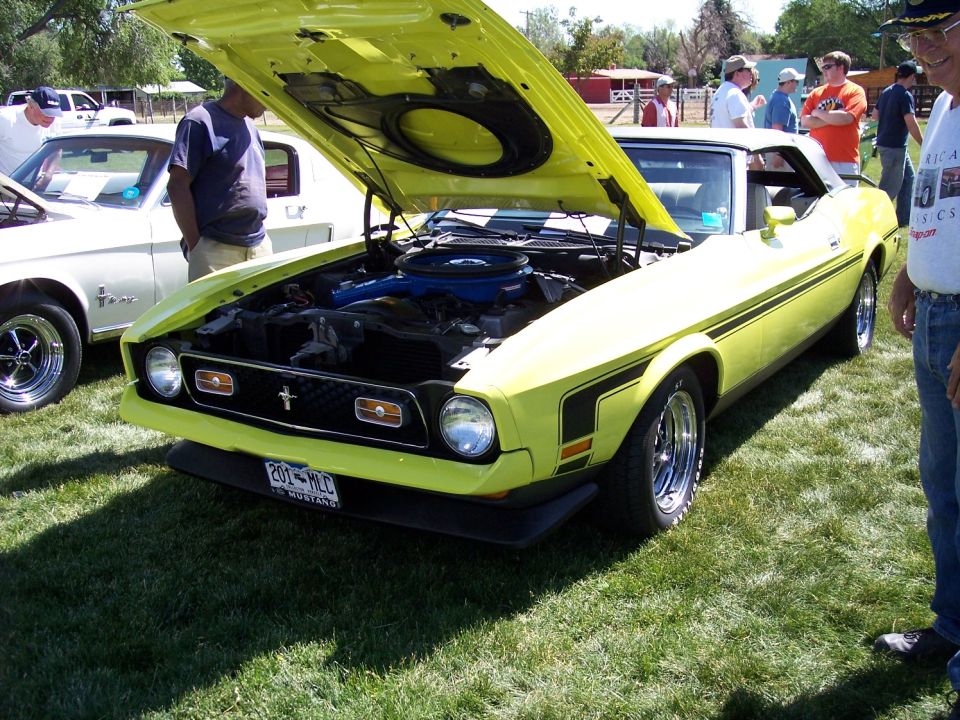 Yellow 1971 Ford Mustang convertible, front 3/4 view, hood open, black stripe on side, chrome wheels