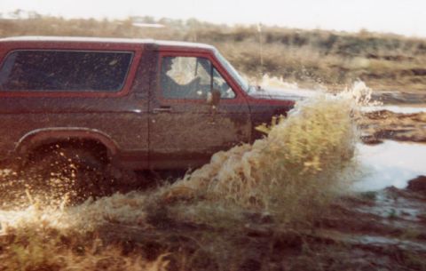 1981 Ford Bronco - A 1981 Ford Bronco kicks up a large spray of water as it navigates through a muddy off-road course.