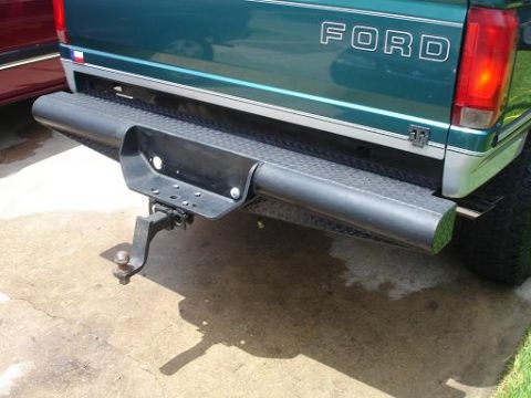 1996 Ford F-150 - The rear of a green Ford truck is shown, a diamond plate bumper and a tow hitch.