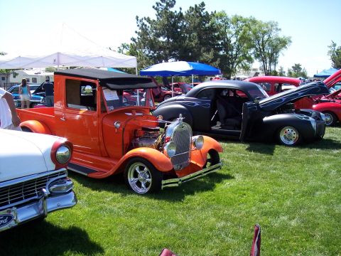 1972 Ford Ranchero - An orange pickup truck with a black convertible top is parked on a grassy field with other vehicles.