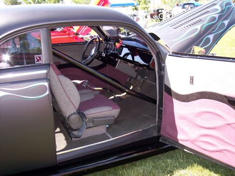 1972 Ford Ranchero - The interior of a modified coupe is visible with its doors and hood open, showing custom upholstery and a roll cage.