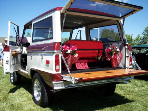 1972 Ford Ranchero - A vintage Ford Bronco is displayed with its tailgate open, decorated with flowers and a 'Please Do Not Touch' sign.