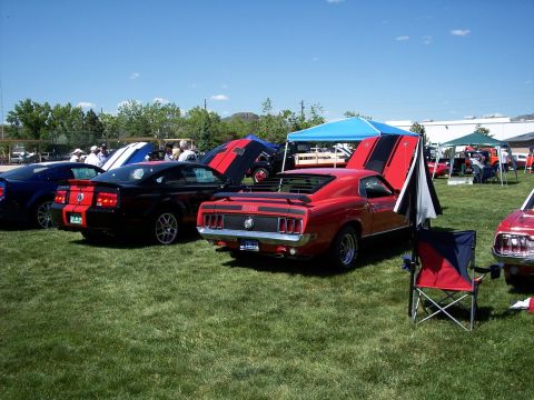 1972 Ford Ranchero - A red 1969 Ford Mustang Mach 1 is parked on grass at a car show with its hood open.