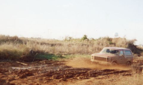 1981 Ford Bronco - Ford Bronco navigating a muddy terrain, likely an off-road trail.