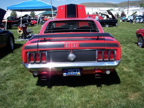 1972 Ford Ranchero - A red 1970 Ford Mustang Mach 1 is parked on grass at an outdoor car show with other vehicles and tents in the background.