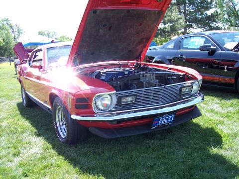 1972 Ford Ranchero - A bright red 1970 Ford Mustang Mach 1 is displayed with its hood open, revealing the engine bay, while a black Mustang sits nearby.