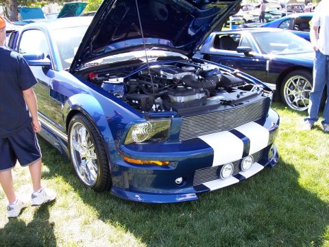 1972 Ford Ranchero - Blue Ford Mustang with racing stripes and hood open, parked on grass at an outdoor event.