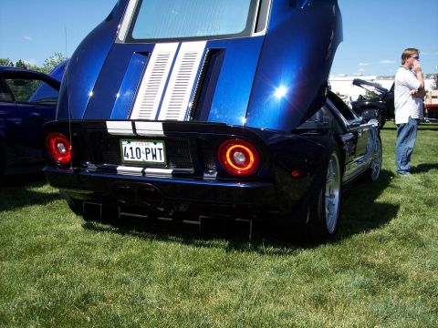1972 Ford Ranchero - Blue 2005 Ford GT with racing stripes and hood open at an outdoor car show.