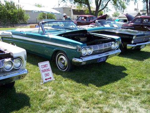 1972 Ford Ranchero - A green 1964 Mercury Comet convertible is parked on the grass with its hood open, alongside other classic cars.