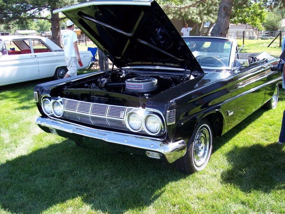 Black 1964 Mercury Marauder convertible with hood open, parked on grass next to a white car