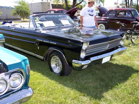 1972 Ford Ranchero - A black convertible with chrome accents and racing wheels is displayed at an outdoor event, with other vehicles in the background.