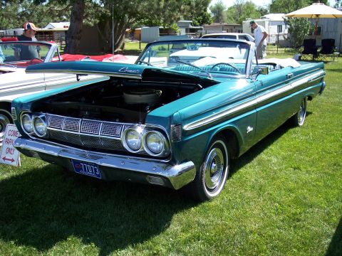 1972 Ford Ranchero - Teal 1964 Mercury Comet convertible at a car show, hood open, with another vehicle nearby.