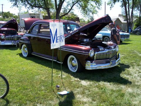 1972 Ford Ranchero - A classic 1949 Mercury Eight is displayed with its hood up at an outdoor event, alongside other vehicles.