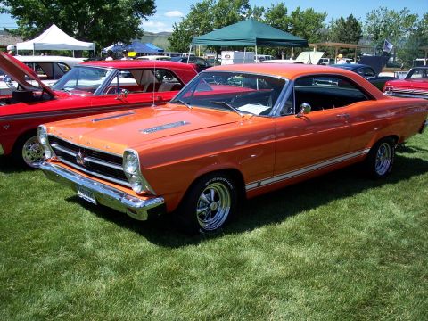 1972 Ford Ranchero - This orange 1967 Ford Ranchero features a distinctive body style and a white side stripe, seen at an outdoor event.