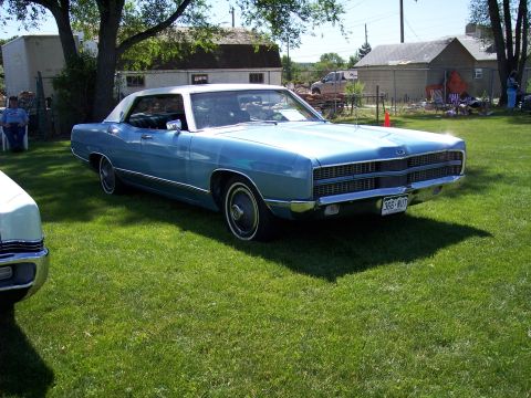 1972 Ford Ranchero - A light blue two-door hardtop with a white vinyl roof sits on a grassy lawn, with a portion of another vehicle visible to the left.