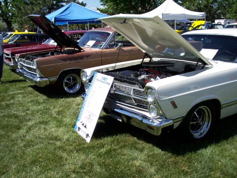 1972 Ford Ranchero - A display board details the 1967 Ford Fairlane, with its hood open at an outdoor car show.