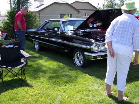 1972 Ford Ranchero - A black 1964 Ford coupe is displayed with its hood open, revealing a custom engine and chrome wheels.