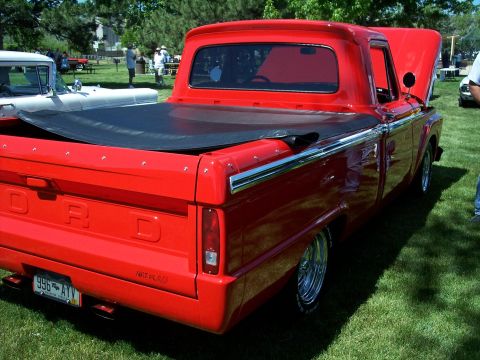 1972 Ford Ranchero - A red Ford pickup truck is parked on a grassy lawn with trees in the background.