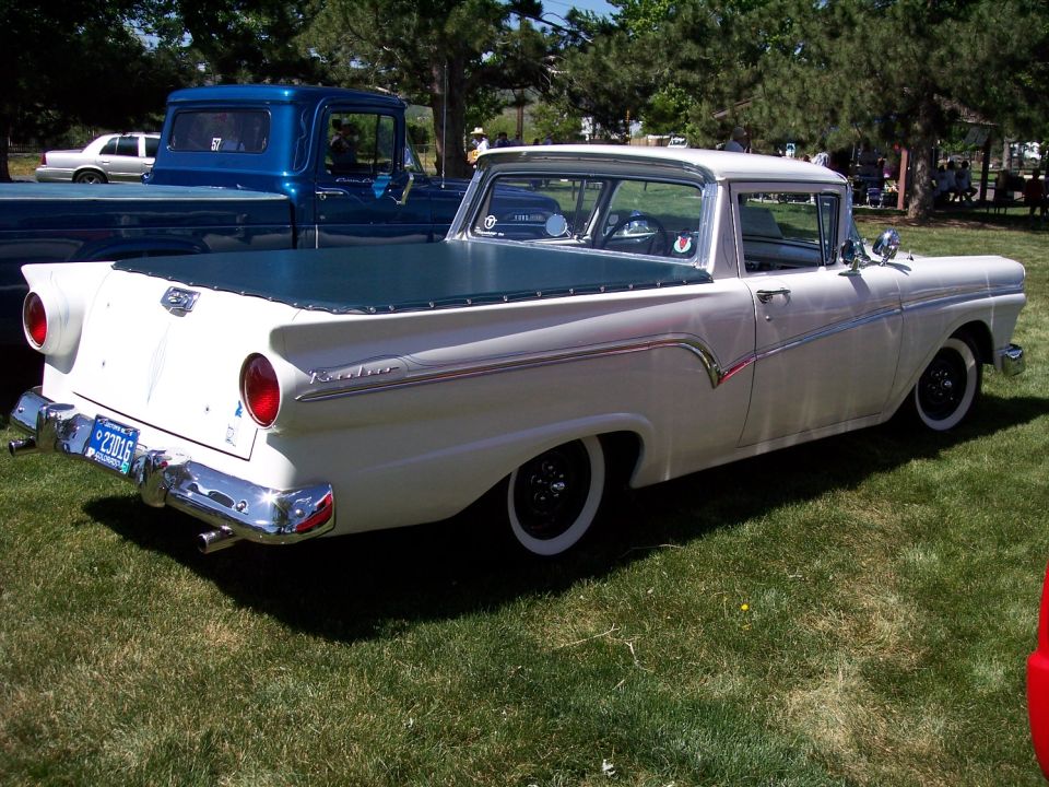White 1957 Ford Ranchero rear three-quarter view with teal tonneau cover on show field