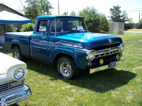 1972 Ford Ranchero - A blue pickup truck is parked on a grassy field next to another vehicle.