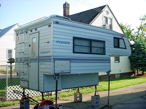 2000 Ford Taurus - A truck camper is shown supported by jacks in a driveway.