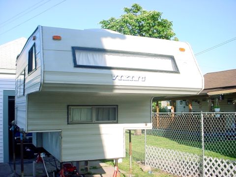 2000 Ford Taurus - A Viking truck camper is shown supported by jacks in a residential yard.