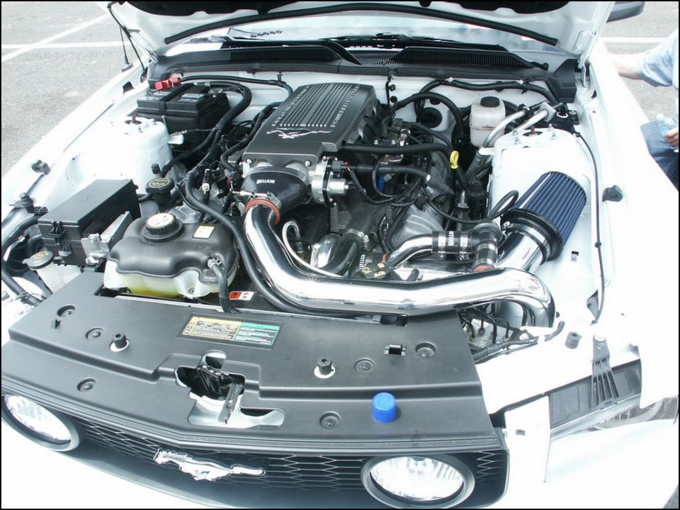 Engine bay with chrome intake and supercharger. Visible text: SUPERMOTORS.NET