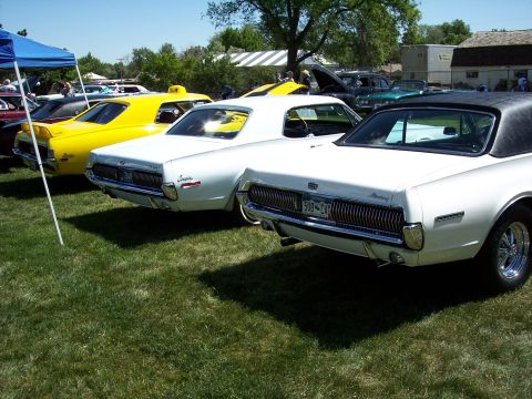 1972 Ford Ranchero - A line of classic cars, including a white Mercury Cougar and a yellow vehicle, are parked on a grassy field under a blue tent.