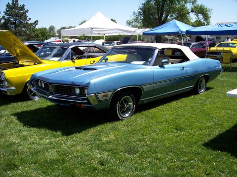 1972 Ford Ranchero - A light blue convertible with a white top is parked on a grassy field next to a yellow car with its hood open.