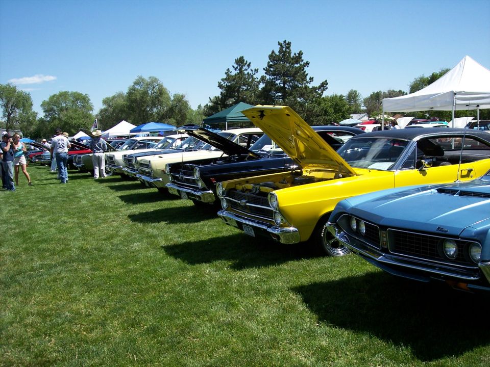 Yellow 1966 Ford Fairlane with hood open, parked on grass next to other classic cars