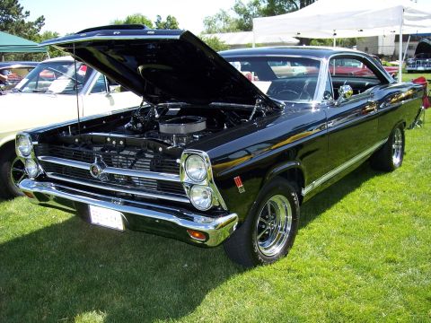 1972 Ford Ranchero - A black classic car is displayed with its hood open, revealing the engine, at an outdoor event.