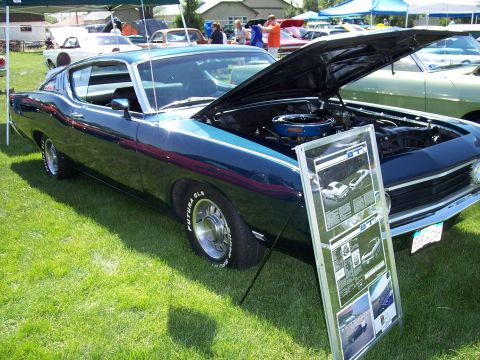 1972 Ford Ranchero - A dark blue 1970 Ford Torino GT is displayed with its hood open at an outdoor event, with a display board in front.