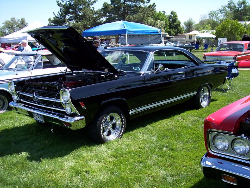 Black 1967 Ford Fairlane with hood open, parked on grass