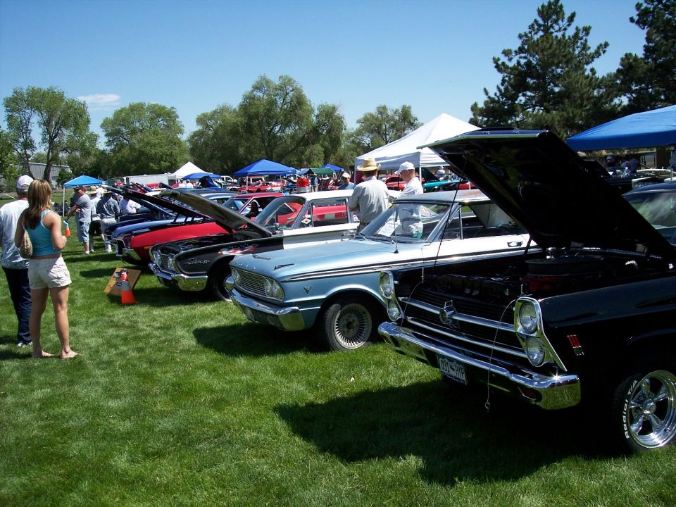 Light blue 1964 Ford Falcon Ranchero with hood open, parked on grass at a car show