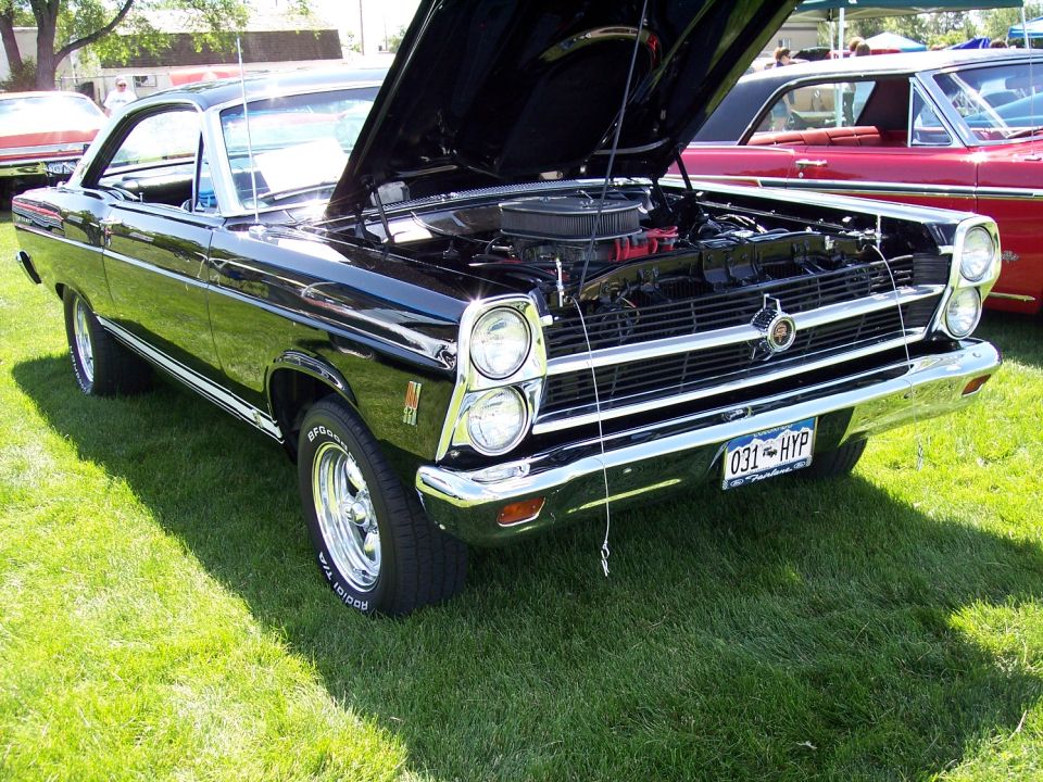 Black 1968 Ford Ranchero with hood open, parked on grass