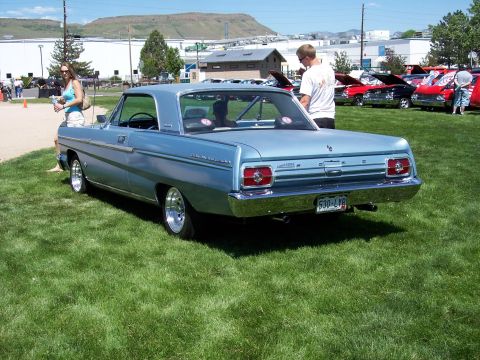 1972 Ford Ranchero - A light blue 1964 Ford Falcon is parked on the grass at an outdoor event with other vehicles in the background.