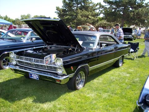 1972 Ford Ranchero - Black 1967 Ford Fairlane at a car show, hood open, parked on grass.