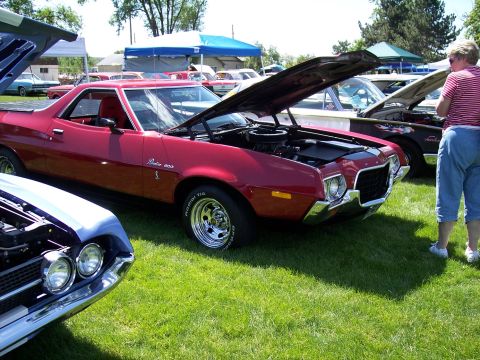 1972 Ford Ranchero - A red pickup truck is displayed with its hood open at an outdoor gathering, with other vehicles present.