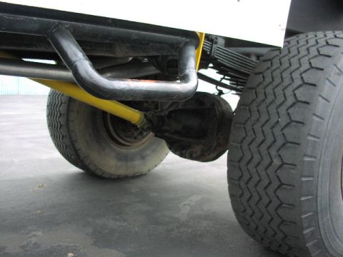 1981 Ford Bronco - The underside of a vehicle shows its rear axle, suspension, and a large tire. A black roll bar is also visible.
