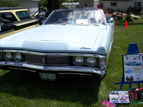1972 Ford Ranchero - A light blue convertible with a distinctive grille and dual headlights is parked on grass, with another vehicle visible behind it.