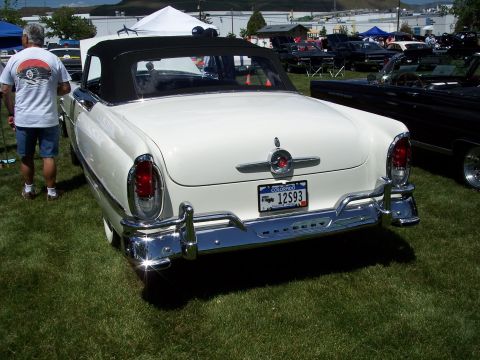 1972 Ford Ranchero - A white convertible with a black top is parked on a grassy field, with other vehicles in the background.