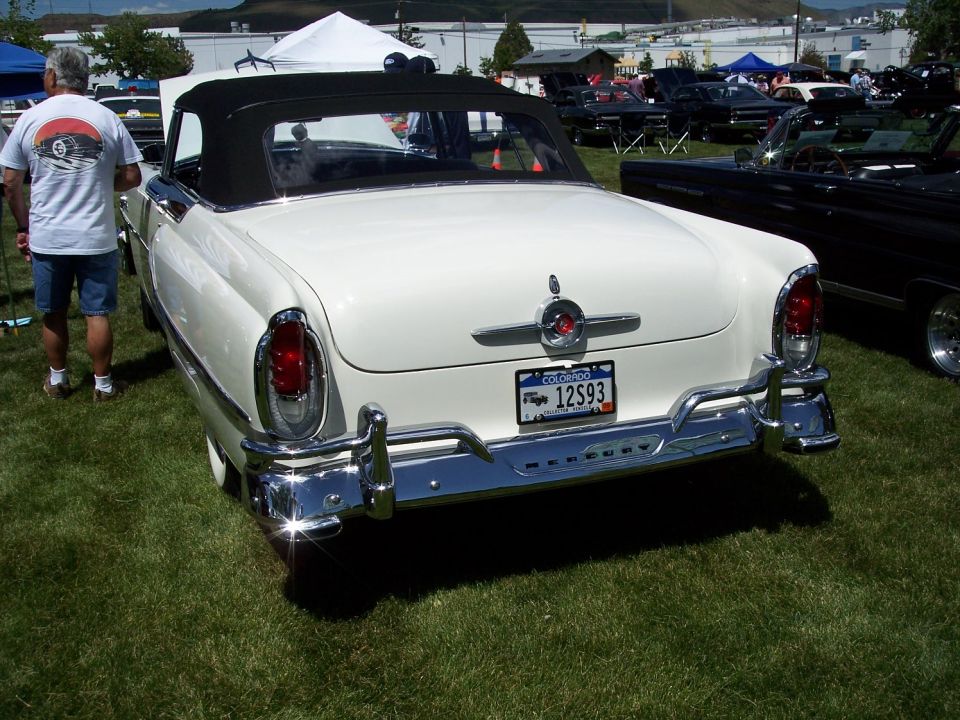 White convertible with a black top parked on grass, rear view, chrome bumper, Colorado license plate 12S93