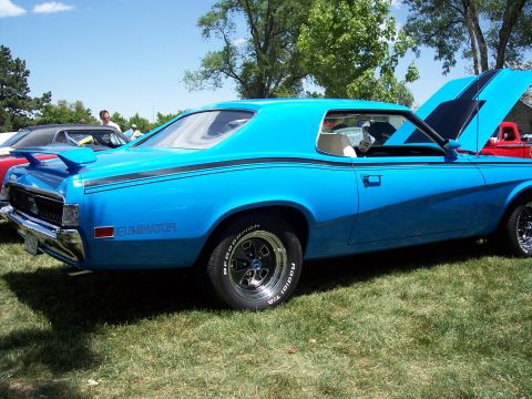 1972 Ford Ranchero - A blue coupe with black racing stripes and "Eliminator" badging is parked on grass at an outdoor event.