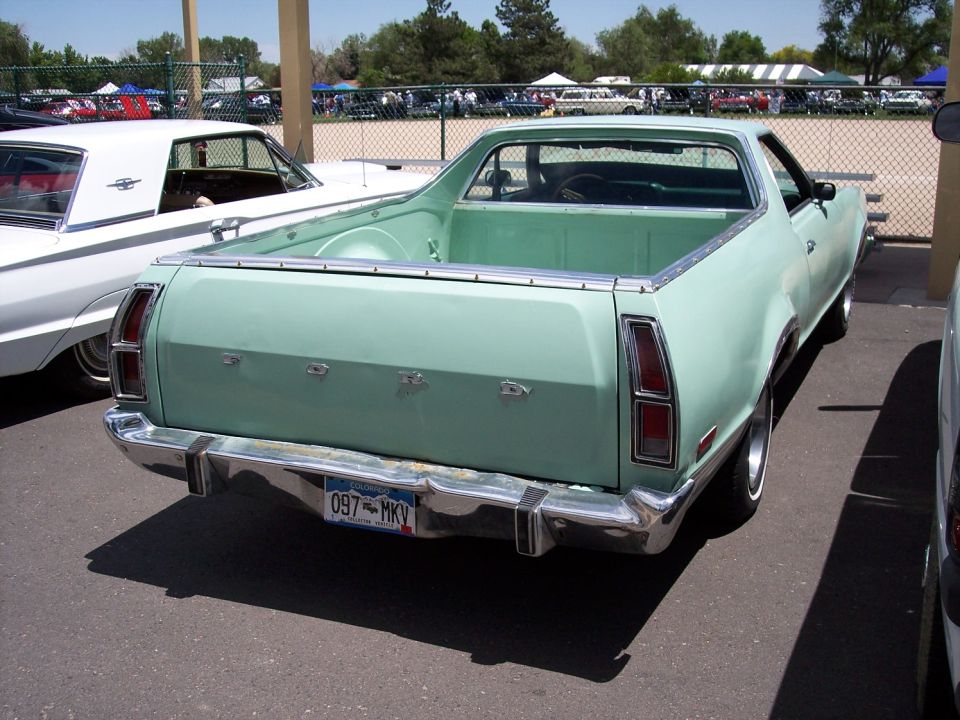Rear view of a light green 1972 Ford Ranchero parked next to a white car
