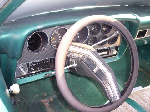 1972 Ford Ranchero - The interior of a vintage vehicle, a green dashboard and steering wheel with visible gauges and a radio.
