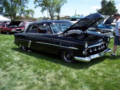1972 Ford Ranchero - A black sedan is displayed with its hood open at an outdoor event.