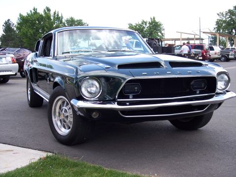 1972 Ford Ranchero - A dark green 1968 Shelby GT500 is shown from the front-three-quarter view, its distinctive grille and hood scoop.
