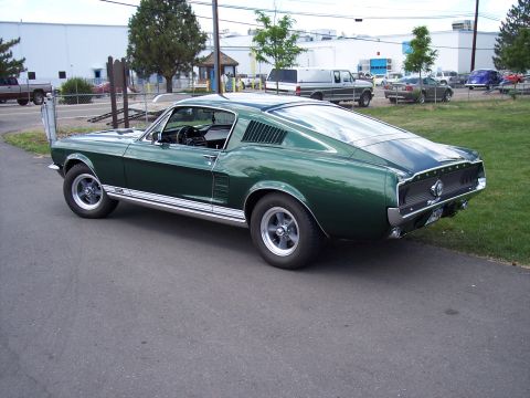 1972 Ford Ranchero - A green 1967 Ford Mustang fastback is seen from a three-quarter front view, parked outdoors.